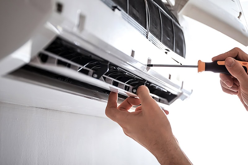Why Are They Called Ductless Mini Splits? Photo of an electrician repairing a ductless HVAC.