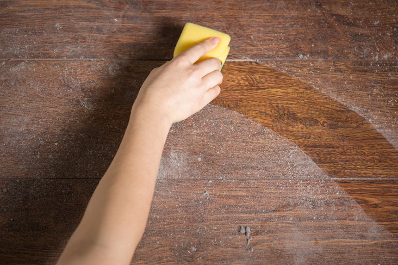 5 Tips to Improve Your Home’s Indoor Air Quality (IAQ) This Winter. Photo of someone wiping off a dusty table with a cloth.